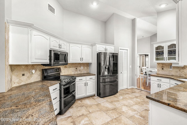 kitchen featuring high vaulted ceiling, appliances with stainless steel finishes, dark stone counters, and white cabinetry