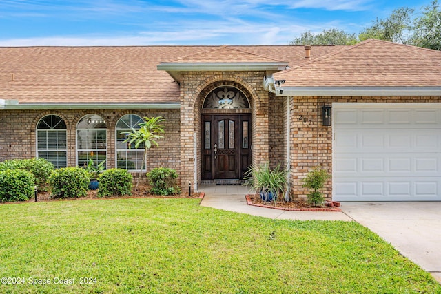 entrance to property with a garage and a yard