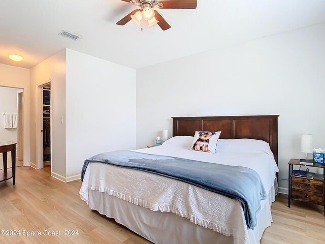 bedroom featuring ceiling fan, a closet, light hardwood / wood-style floors, and a walk in closet