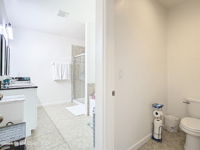 bathroom featuring vanity, toilet, a shower with door, and tile patterned floors