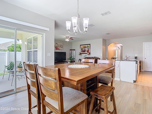 dining room with ceiling fan with notable chandelier and light wood-type flooring