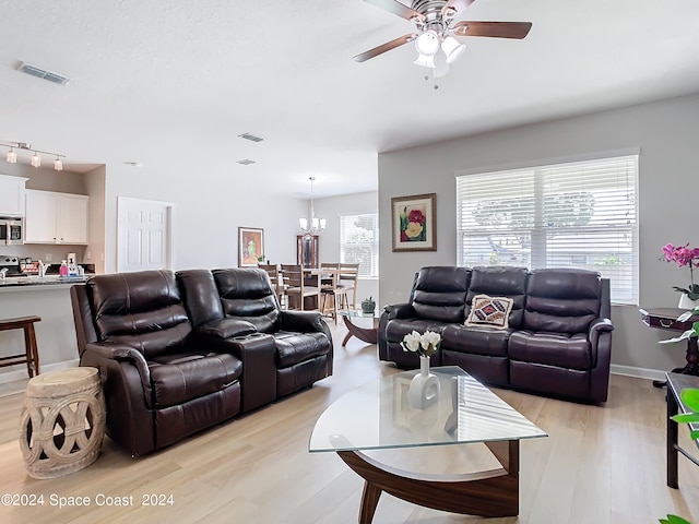 living room with ceiling fan with notable chandelier and light hardwood / wood-style floors