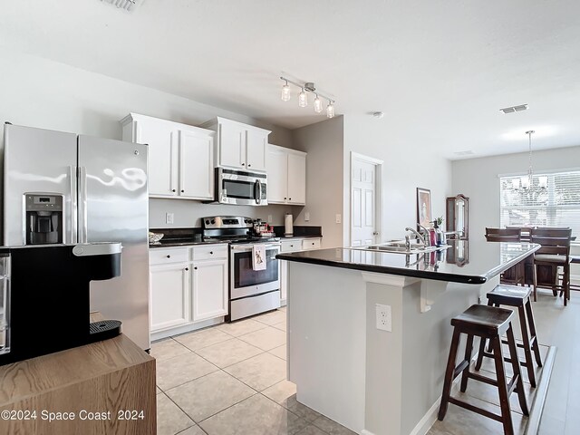 kitchen with white cabinetry, appliances with stainless steel finishes, a kitchen island with sink, and a breakfast bar area