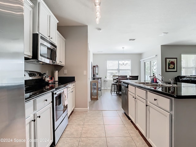 kitchen featuring white cabinetry, an island with sink, stainless steel appliances, decorative light fixtures, and sink