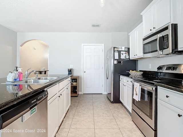 kitchen with appliances with stainless steel finishes, sink, light tile patterned floors, and white cabinets