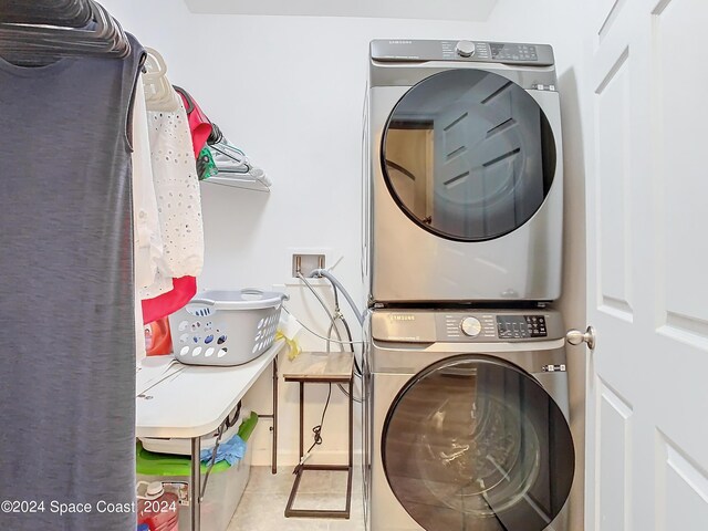 laundry room featuring stacked washer / dryer and light tile patterned floors