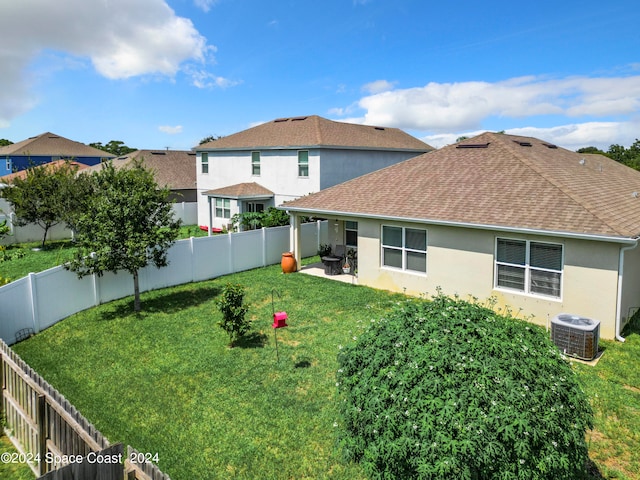 rear view of property featuring a yard, central AC, and a patio area