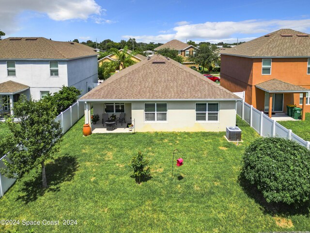 rear view of property featuring a lawn, central AC, and a patio area