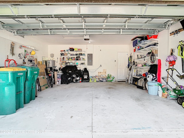 garage with a garage door opener, a workshop area, and electric panel