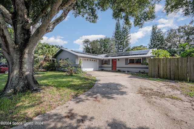 ranch-style home with a front yard, solar panels, and a garage