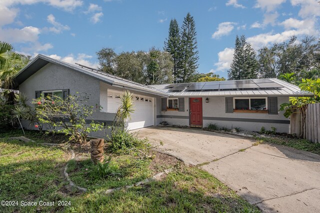 single story home with solar panels and a garage