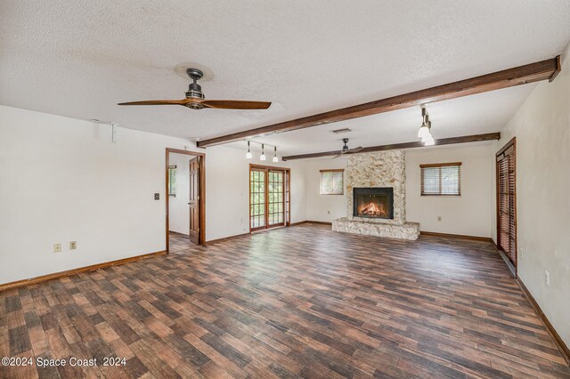 unfurnished living room with ceiling fan, a textured ceiling, a fireplace, and dark wood-type flooring