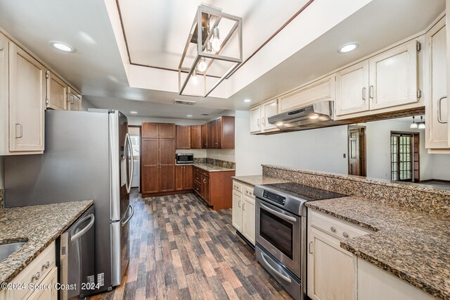 kitchen with appliances with stainless steel finishes, stone counters, dark wood-type flooring, and exhaust hood