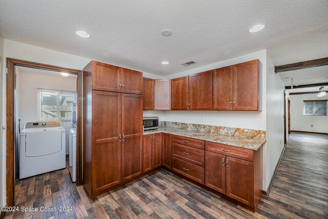 kitchen with a textured ceiling, light stone countertops, dark hardwood / wood-style flooring, and washer and dryer