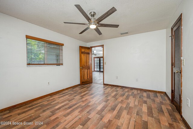 empty room with ceiling fan, a textured ceiling, and dark wood-type flooring