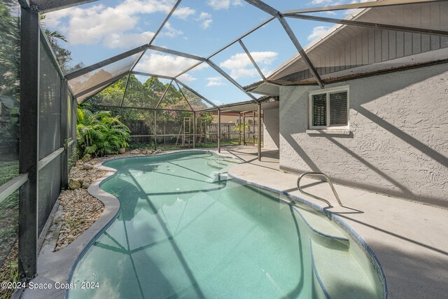 view of pool with glass enclosure and a patio area