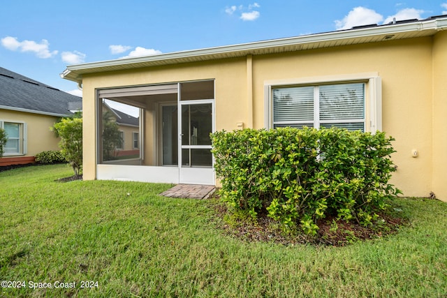 rear view of property with a sunroom and a yard