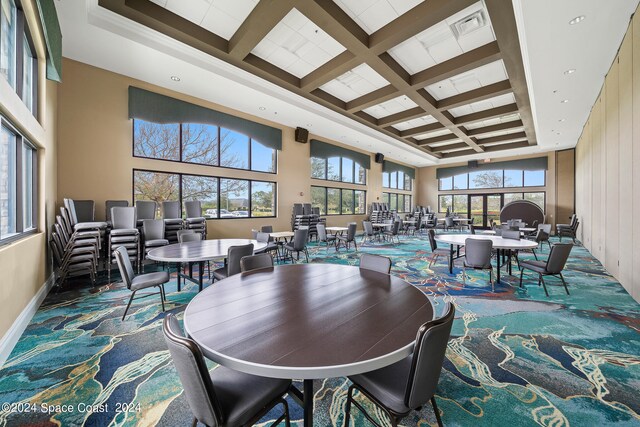 dining area with a towering ceiling, carpet floors, and coffered ceiling