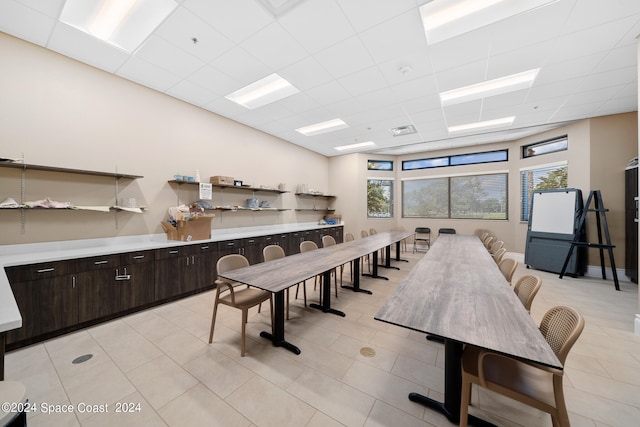 dining space with a drop ceiling and light tile patterned floors