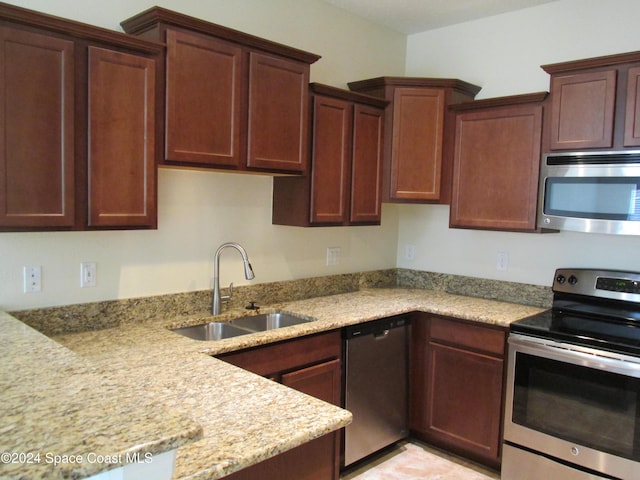 kitchen featuring light stone counters, sink, and stainless steel appliances