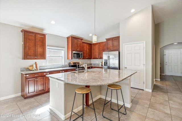 kitchen with a kitchen bar, appliances with stainless steel finishes, sink, decorative light fixtures, and an island with sink