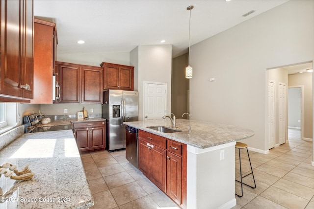 kitchen with light stone counters, stainless steel appliances, light tile patterned floors, decorative light fixtures, and an island with sink