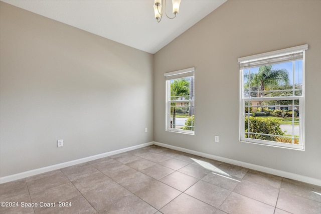 empty room with light tile patterned floors, high vaulted ceiling, and a notable chandelier