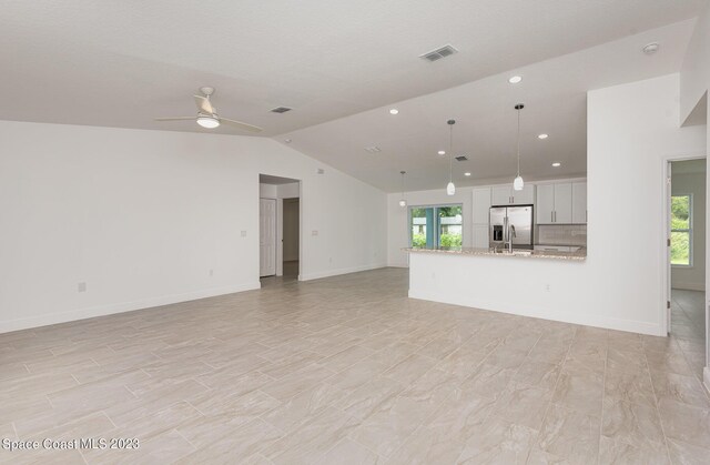 unfurnished living room featuring vaulted ceiling, a sink, baseboards, visible vents, and ceiling fan