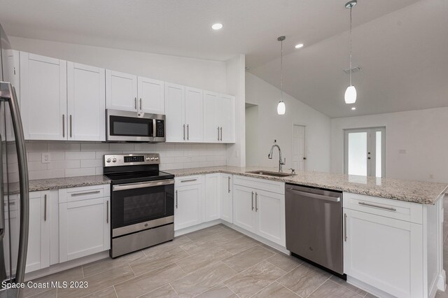 kitchen featuring sink, white cabinets, lofted ceiling, hanging light fixtures, and stainless steel appliances