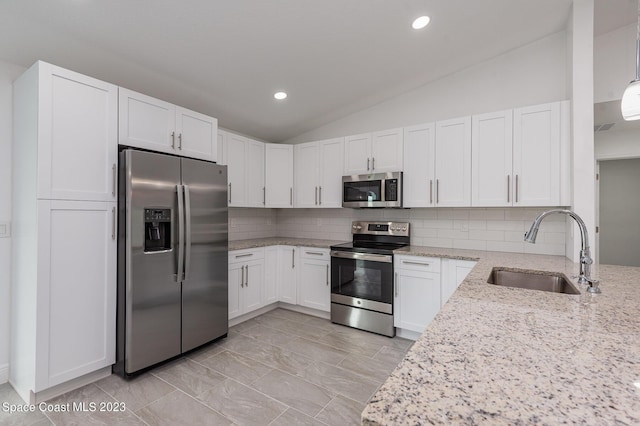 kitchen with vaulted ceiling, a sink, light stone countertops, tasteful backsplash, and stainless steel appliances