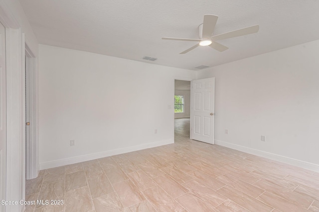 unfurnished room with baseboards, visible vents, and a ceiling fan