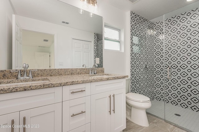 bathroom with visible vents, a sink, toilet, and a stall shower