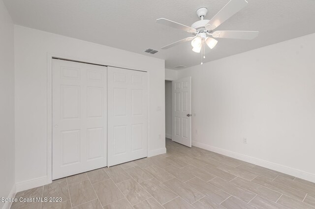 unfurnished bedroom featuring ceiling fan, a textured ceiling, and a closet