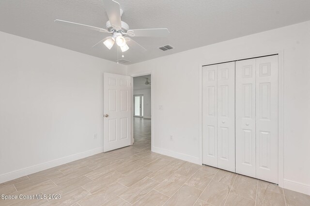 unfurnished bedroom featuring ceiling fan, a textured ceiling, a closet, and light hardwood / wood-style flooring