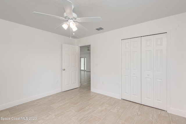 unfurnished bedroom with baseboards, a textured ceiling, ceiling fan, visible vents, and a closet