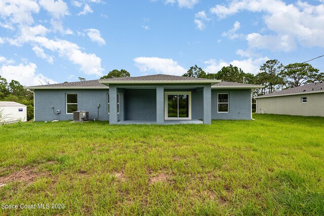 rear view of house featuring central AC and a yard