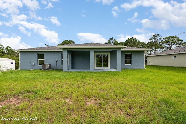 back of house with a lawn, central AC, and stucco siding