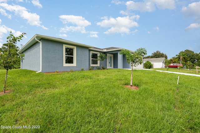 single story home with a garage, driveway, stucco siding, and a front lawn