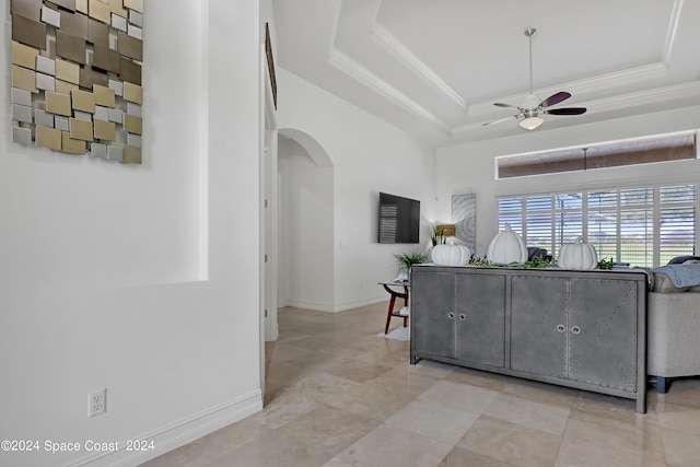 living room with a raised ceiling, crown molding, and ceiling fan