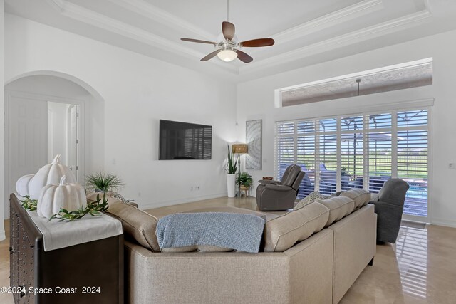 living room featuring ceiling fan, a raised ceiling, and crown molding