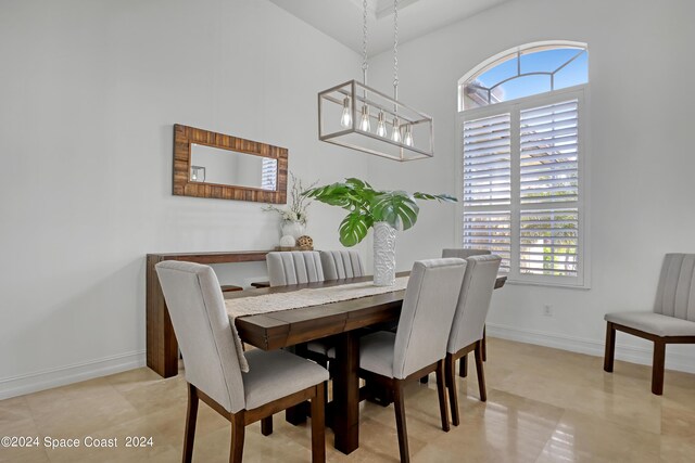 dining space with a notable chandelier, a towering ceiling, light tile patterned floors, and a wealth of natural light