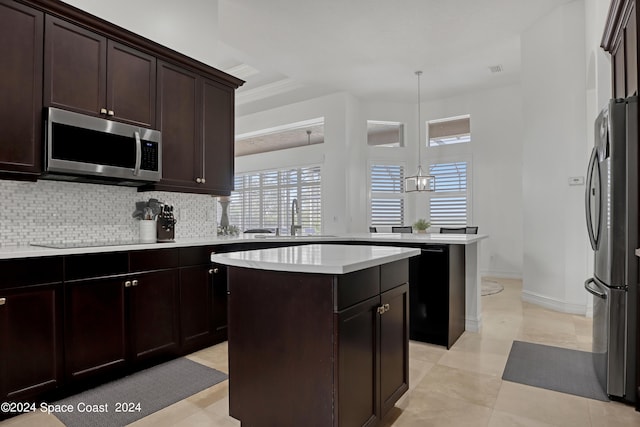 kitchen with hanging light fixtures, sink, stainless steel appliances, a center island, and a notable chandelier