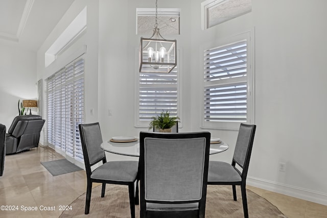 tiled dining space with a notable chandelier, plenty of natural light, and ornamental molding