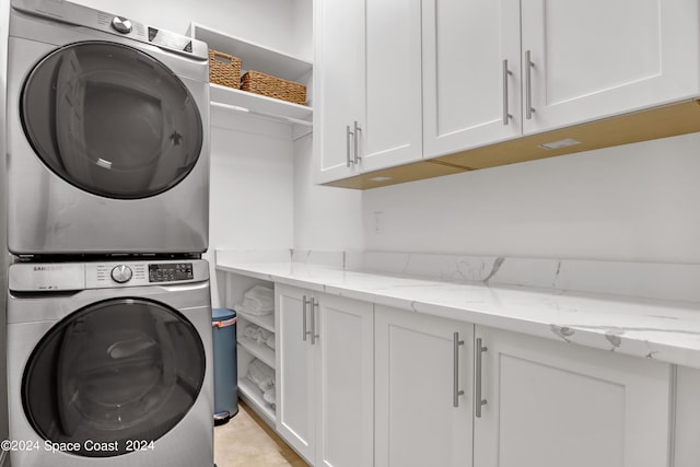 washroom with cabinets and stacked washing maching and dryer