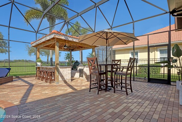 exterior space featuring glass enclosure, an outdoor bar, ceiling fan, and a patio area