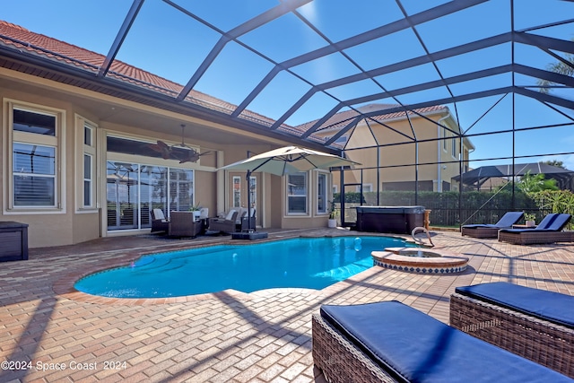 view of pool featuring glass enclosure, a hot tub, and a patio area