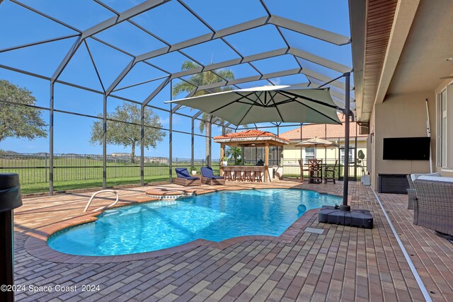 view of swimming pool with a hot tub, glass enclosure, and a patio