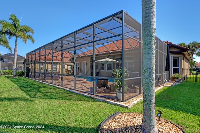 rear view of house featuring a lawn, a lanai, a fenced in pool, and a patio area