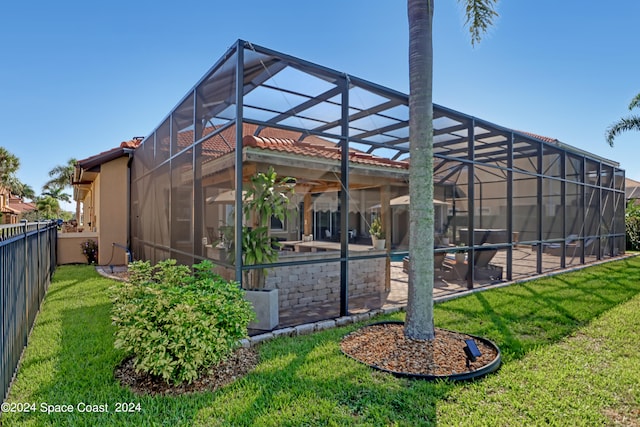 rear view of property featuring a patio, a yard, and a lanai