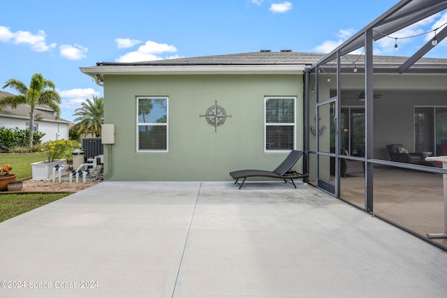 rear view of house with glass enclosure and a patio area